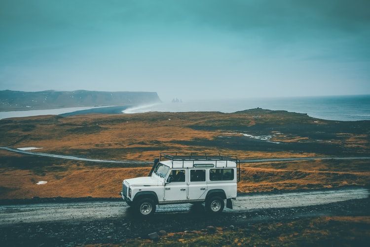 View of a white 4x4 on a road in a wild landscape